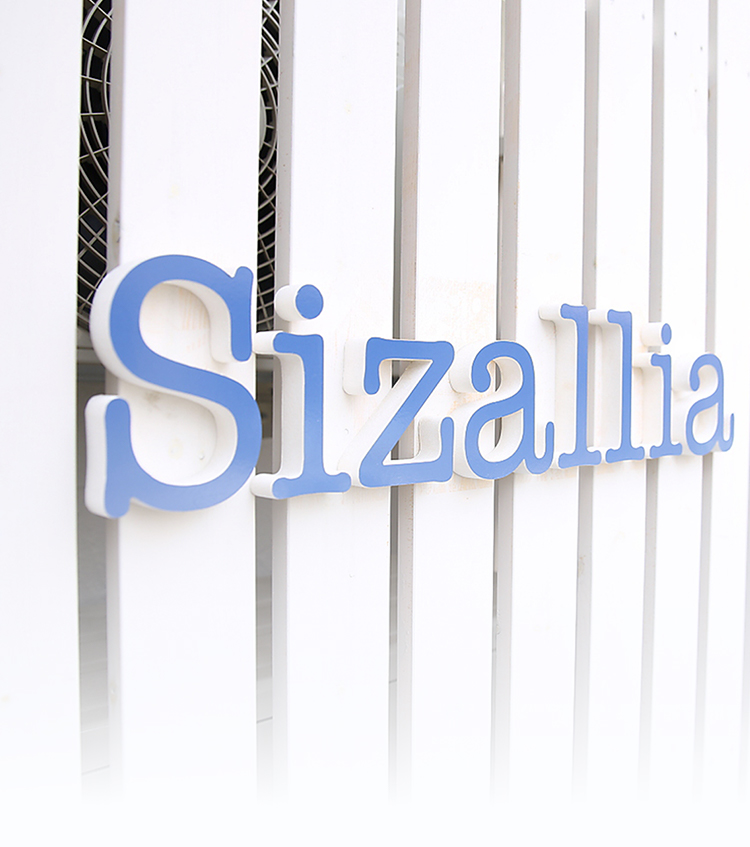 白い外壁に取り付けられたSizalliaの立体看板
